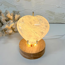 Load image into Gallery viewer, Clear Quartz crystal heart illuminated on a wooden LED light base
